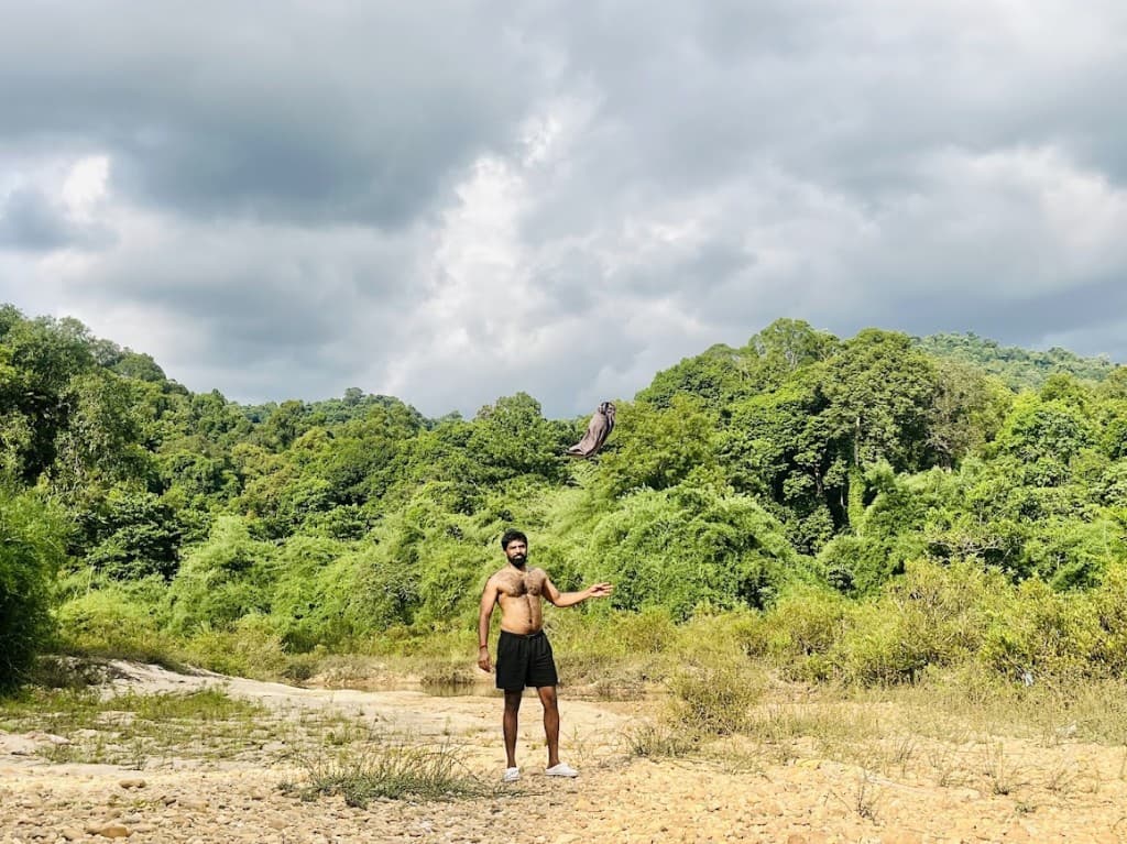 On a stony riverbed, green hills behind.