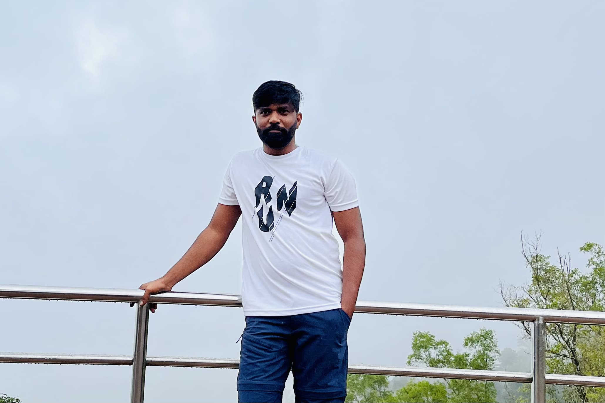 Anand at a metal railing, fog behind the trees.