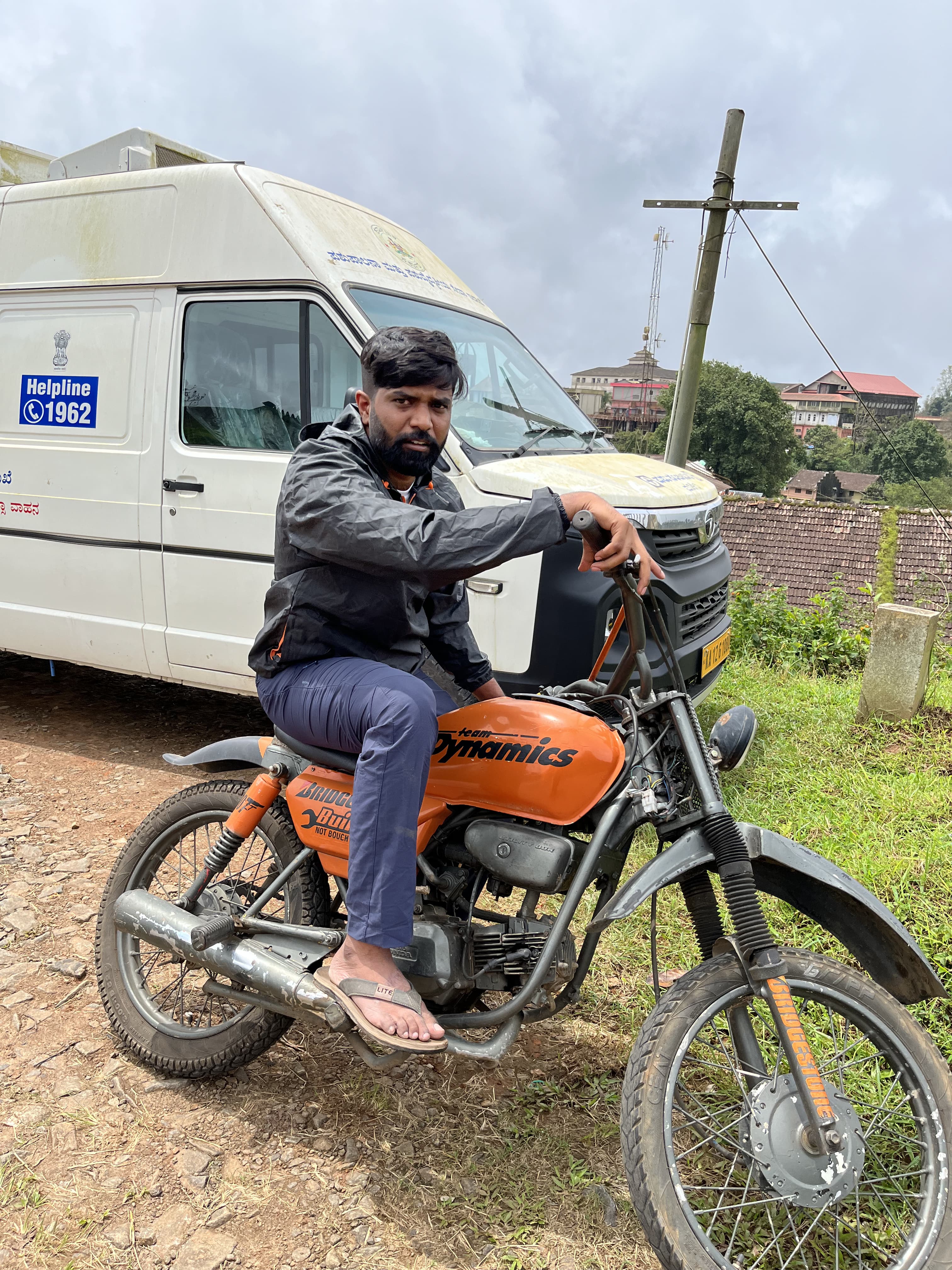 Anand on the motorcycle beside a white van.