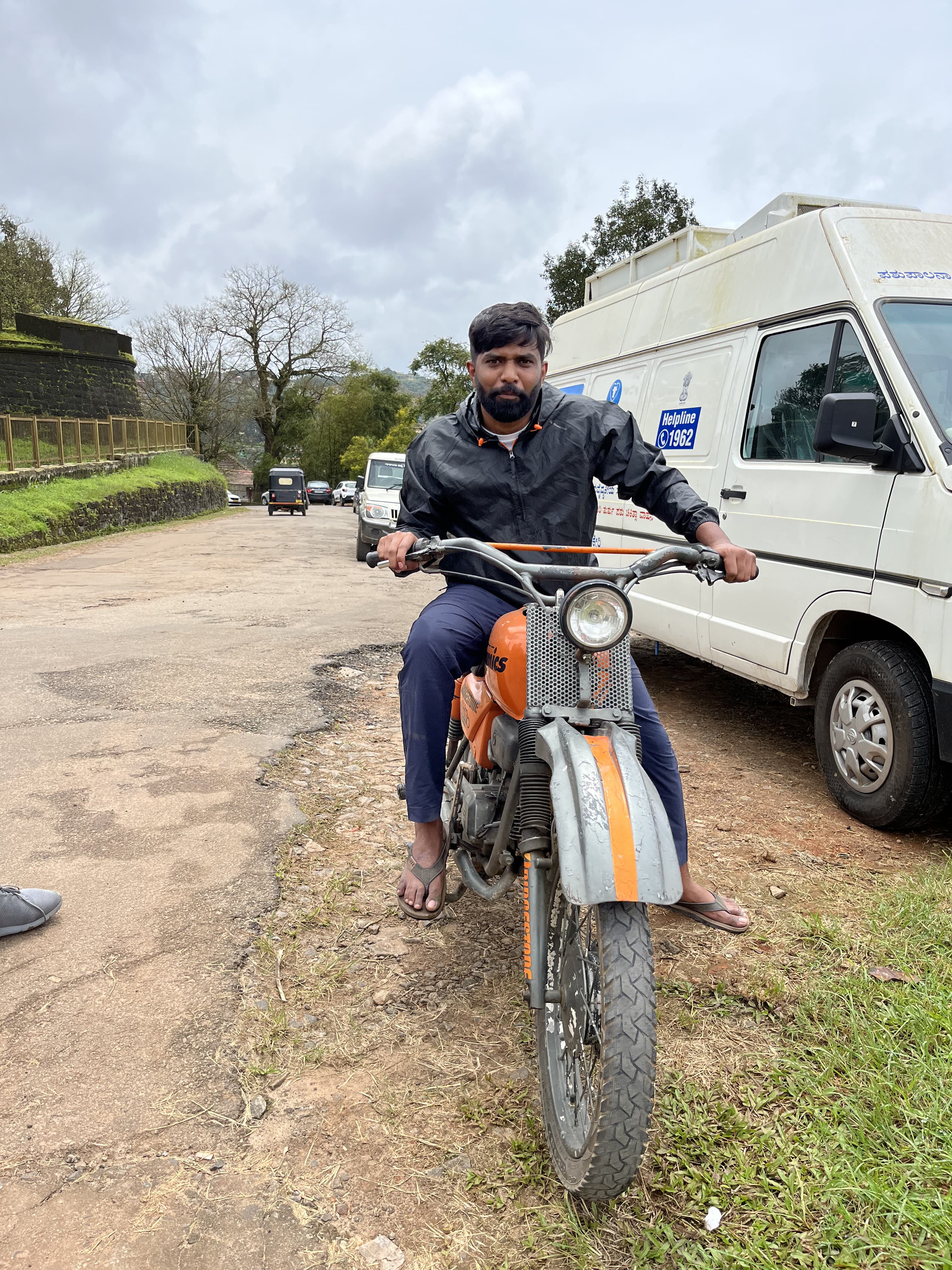 Anand sitting on a motorcycle in Coorg.