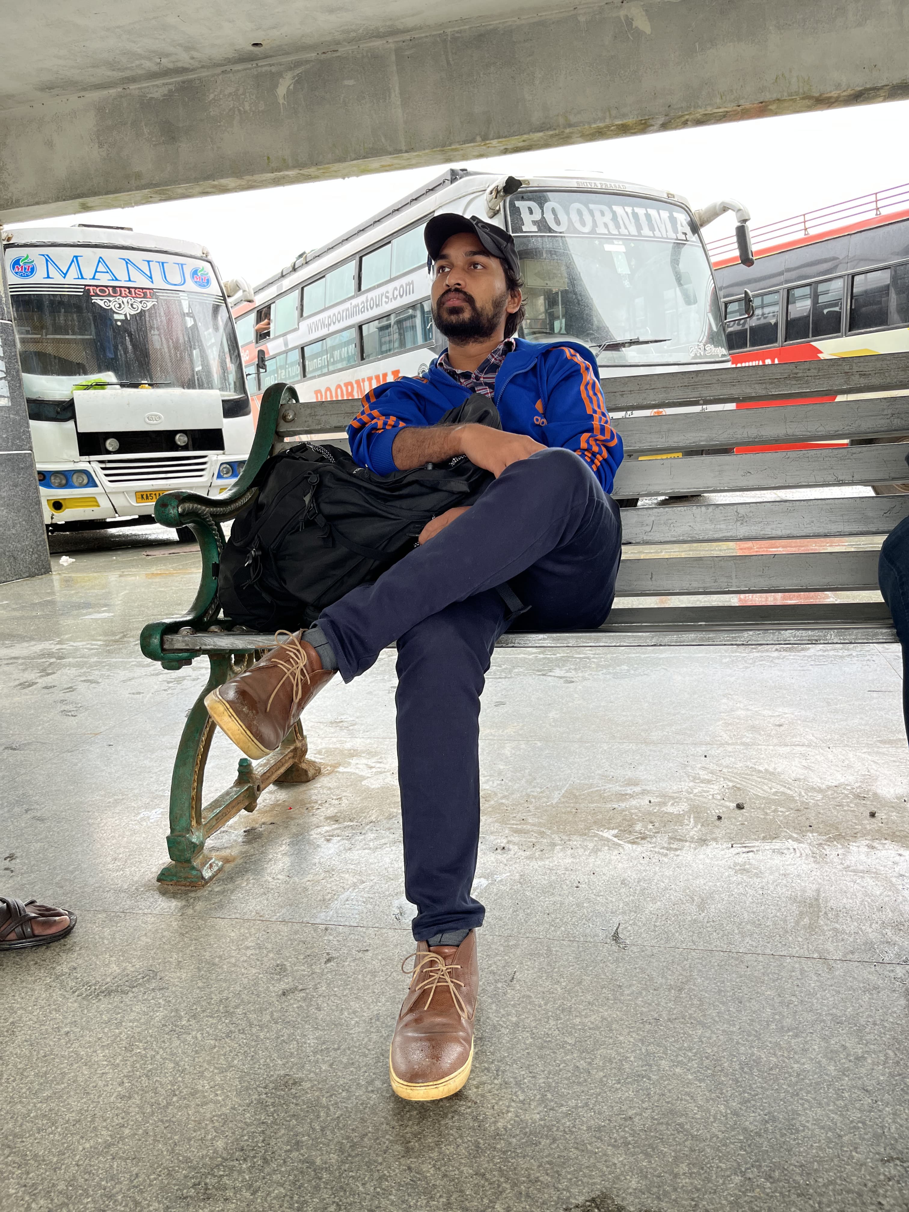 Bharat in a blue jacket, sitting on a bench.