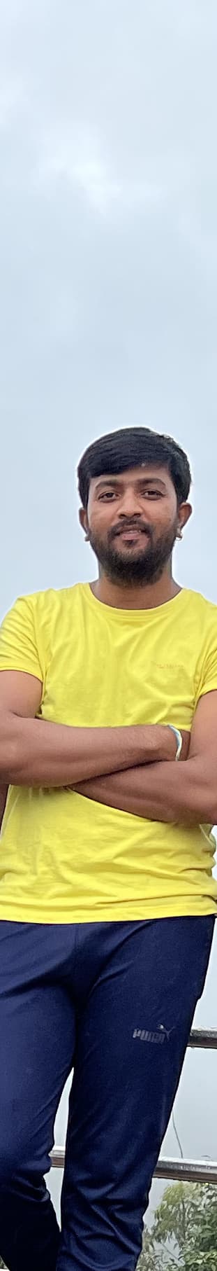 Sunil in a yellow t-shirt at a misty railing in Coorg.
